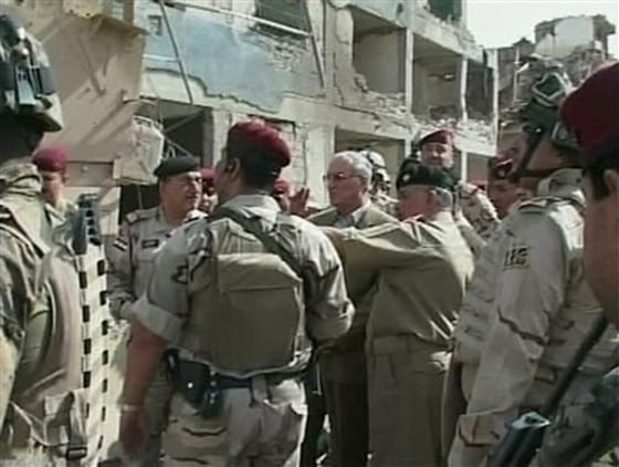 Iraqi Defense Minister Abdul-Qadir al-Ubaidi, center, inspects the site of a suicide attack accompanied by soldiers at a military headquarters in Baghdad, on Sunday. The fighting killed 12 people and wounded dozens.